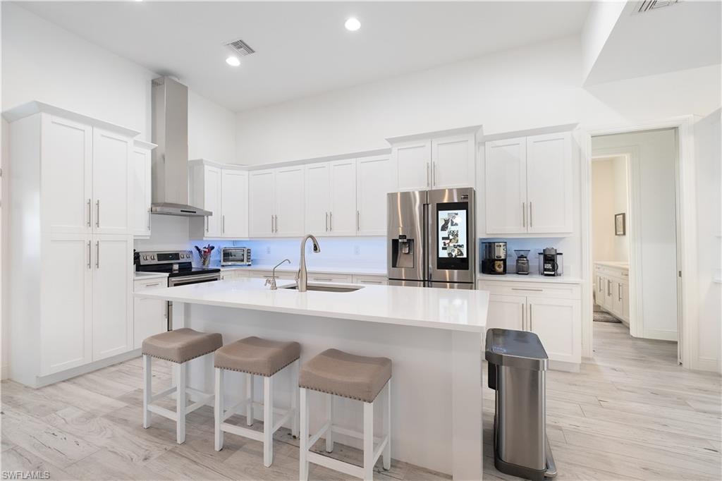 693 7th Street Northwest Naples, FL 34120 - Photo 9 of 32 a kitchen with cabinets a sink and chairs