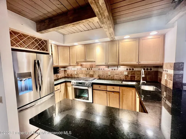 a kitchen with stainless steel appliances granite countertop a sink a stove and a refrigerator