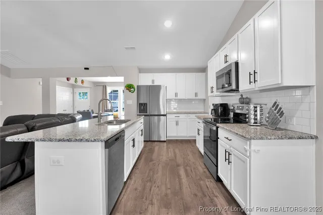 a kitchen with granite countertop kitchen island white cabinets stainless steel appliances and a sink