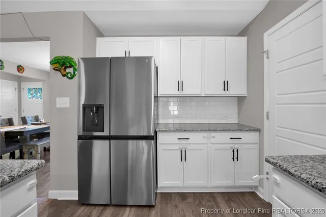 a kitchen with stainless steel appliances granite countertop a refrigerator sink and white cabinets
