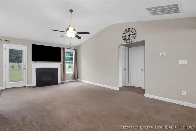 a view of a livingroom with a fireplace a flat screen tv and a ceiling fan