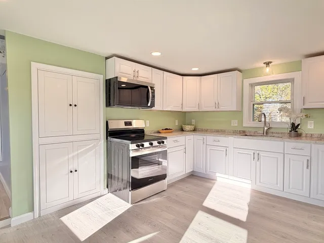 a kitchen with granite countertop a sink cabinets stainless steel appliances and a window