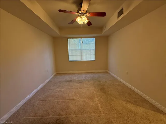 a view of an empty room and window and chandelier fan