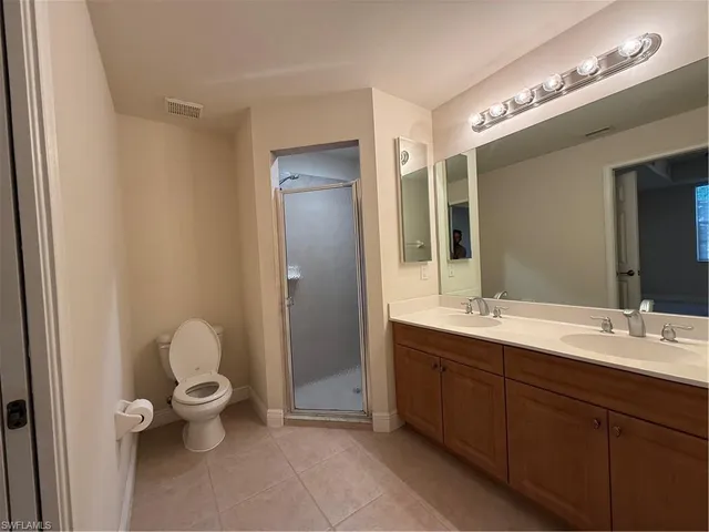 a spacious bathroom with a double vanity sink a mirror and a toilet