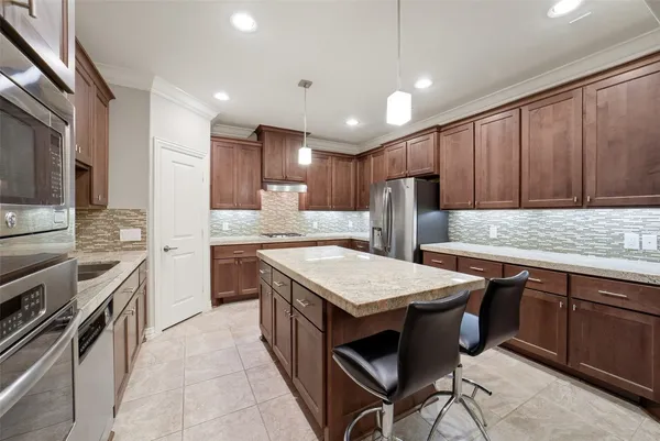 a kitchen with stainless steel appliances granite countertop a table chairs sink refrigerator and microwave