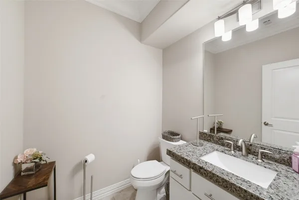 a bathroom with a granite countertop sink a toilet and a mirror