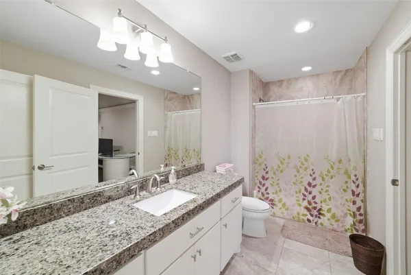 a bathroom with a granite countertop sink a toilet and a large mirror