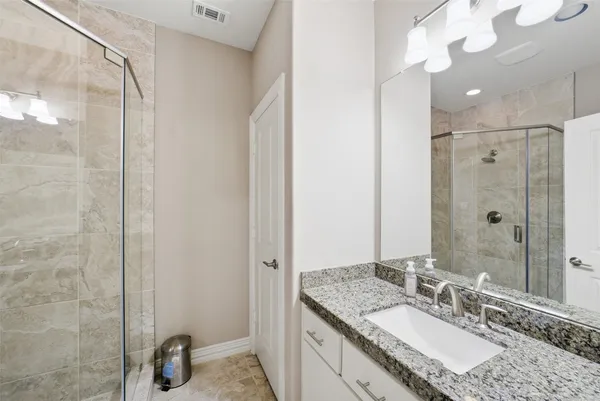 a bathroom with a granite countertop sink a mirror and shower