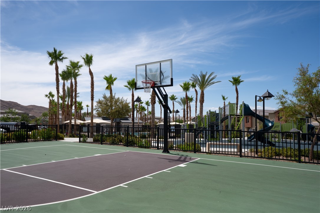 12267 Desert Light Road, Unit 4 Las Vegas, NV 89183 - Photo 18 of 18 An outdoor basketball court and adjacent playground await, surrounded by mature palm trees under an expansive sky.