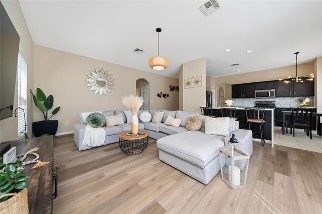 a living room with furniture kitchen view and a wooden floor