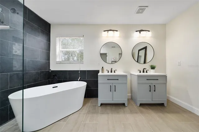 a bathroom with a double vanity sink mirror and bathtub