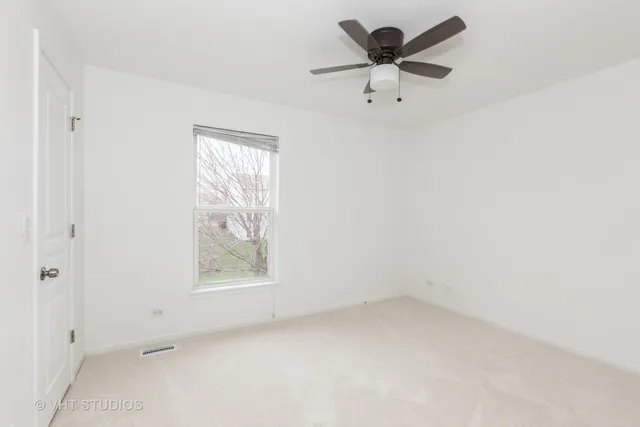 an empty room with a window and a ceiling fan