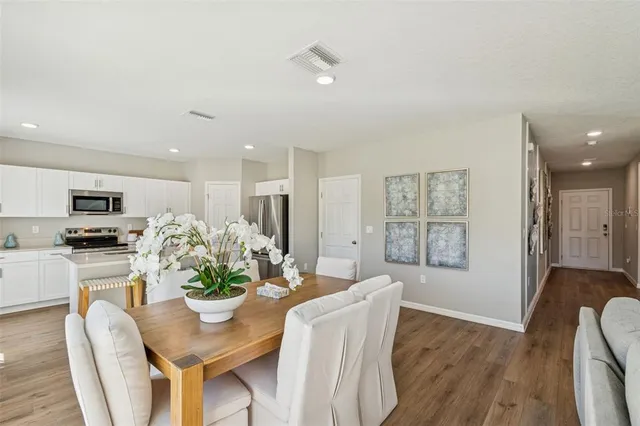 a kitchen with stainless steel appliances a refrigerator a stove a sink dishwasher and white cabinets with wooden floor