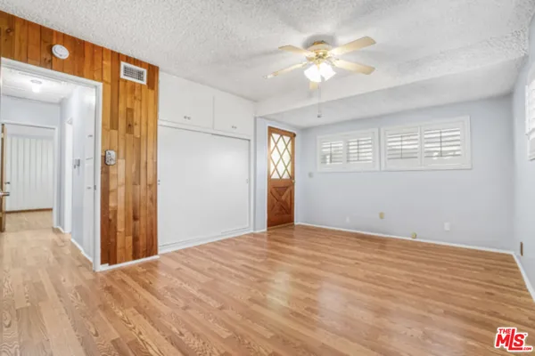 a view of an empty room with chandelier fan and wooden floor