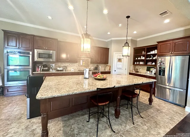 a kitchen with stainless steel appliances kitchen island granite countertop a table chairs sink and cabinets