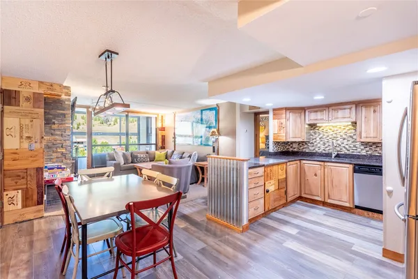 a kitchen with stainless steel appliances a dining table chairs stove and white cabinets
