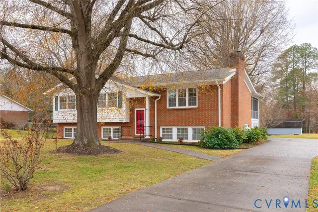 a front view of a house with large trees and plants