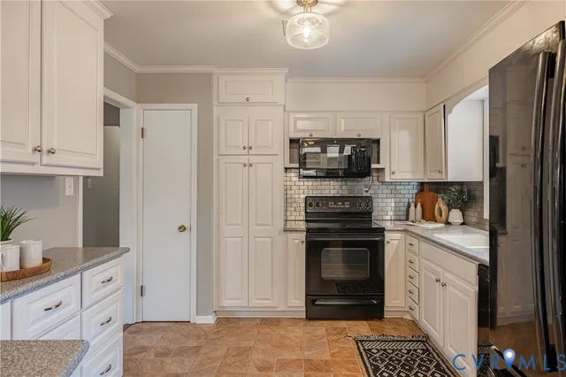 a kitchen with granite countertop a refrigerator stove and white cabinets