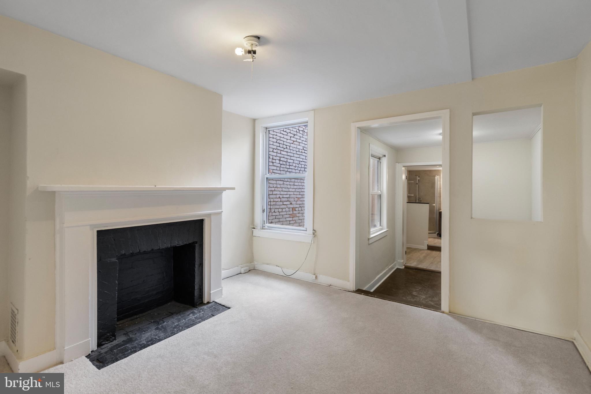 119 South Poppleton Street Baltimore, MD 21201 - Photo 18 of 27 an empty room with a fireplace and wooden floor
