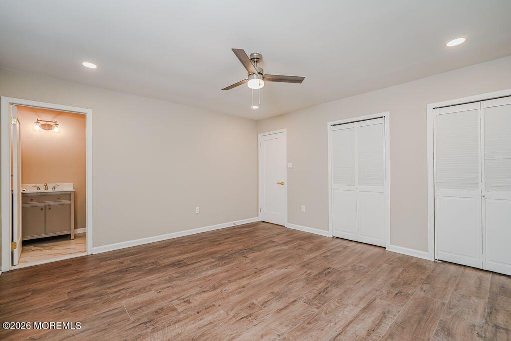 3 Gatley Close, Unit 1000 Freehold, NJ 07728 - Photo 12 of 24 an empty room with wooden floor a ceiling fan and kitchen view