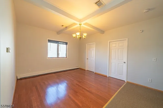 an empty room with a chandelier fan and windows
