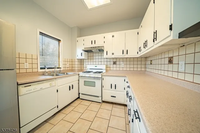a kitchen with granite countertop white cabinets and white appliances