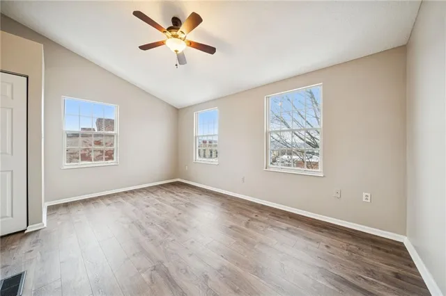 a view of an empty room with window and wooden floor