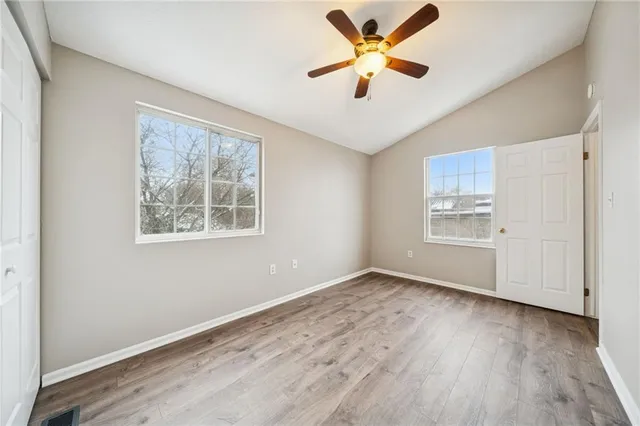 a view of an empty room with window and wooden floor