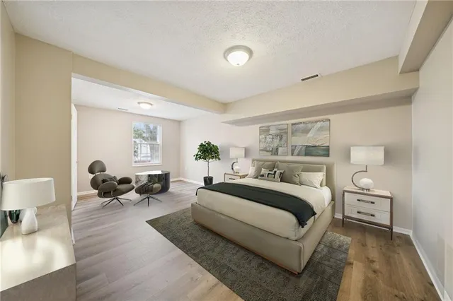 a spacious bedroom with a bed and lamp