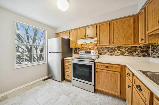a kitchen with stainless steel appliances granite countertop a refrigerator stove and sink