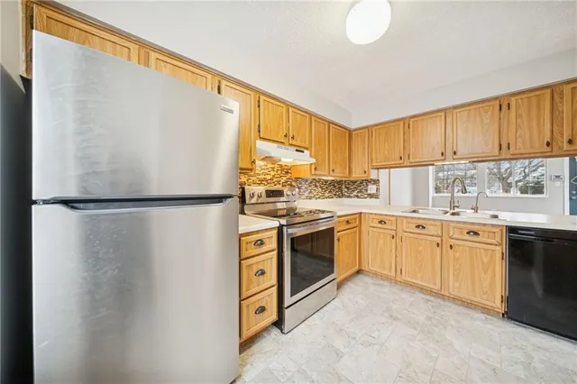 a kitchen with stainless steel appliances granite countertop a refrigerator sink stove and cabinets