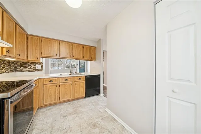 a kitchen with granite countertop a sink stove and cabinets