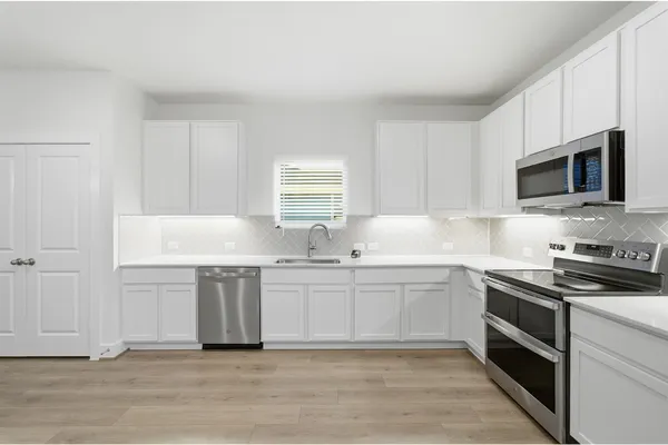 a kitchen with granite countertop a sink stainless steel appliances and white cabinets