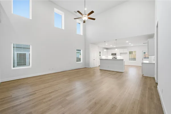 a view of an empty room with a kitchen and wooden floor
