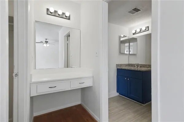 a view of an empty room with wooden floor and a ceiling fan