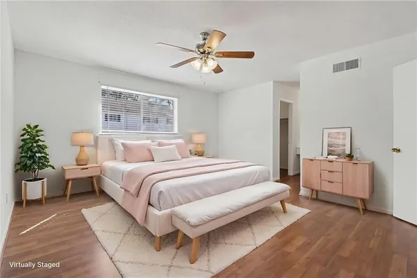 an empty room with wooden floor and a ceiling fan