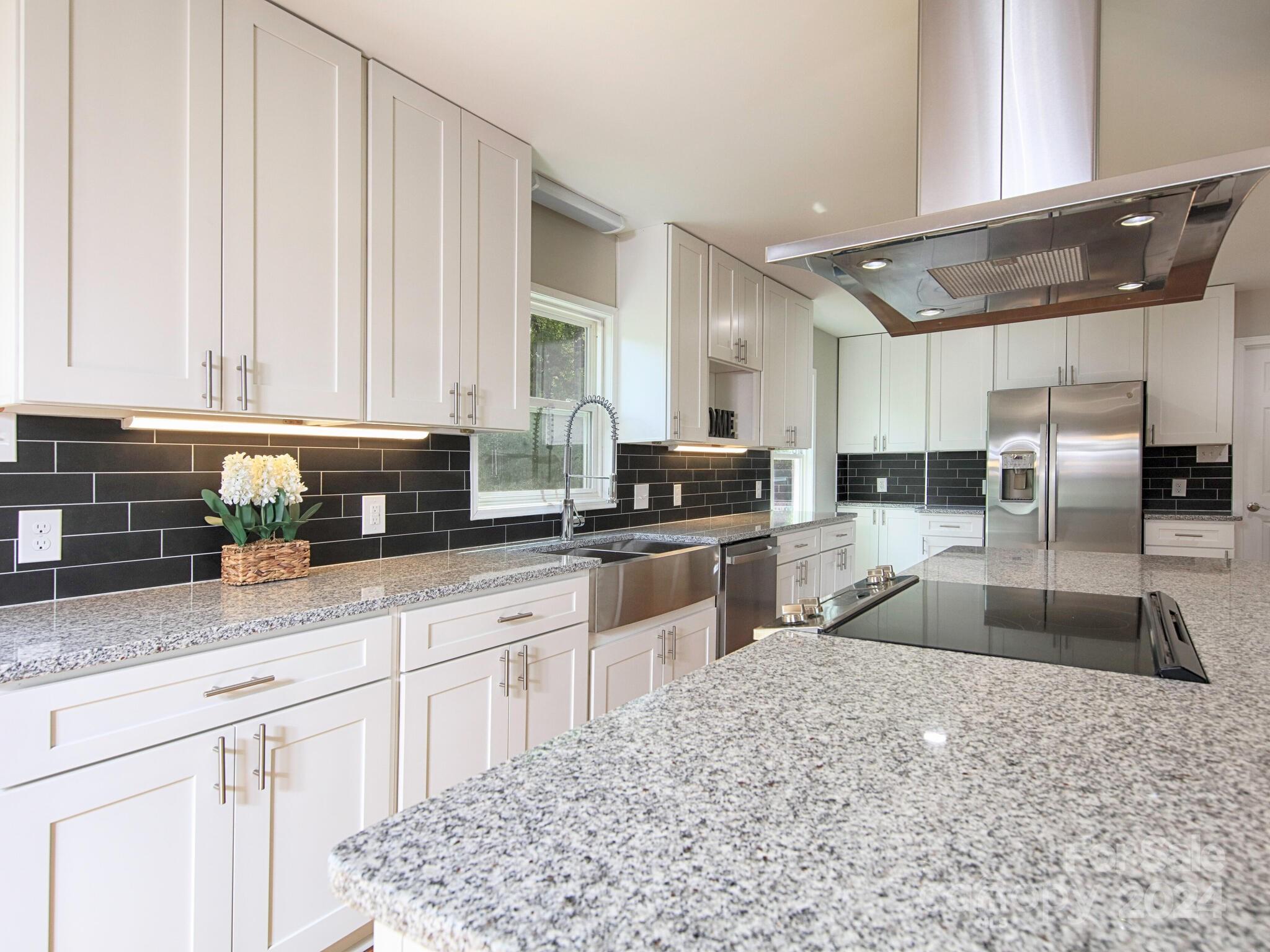 a kitchen with granite countertop a sink a counter top space appliances and cabinets