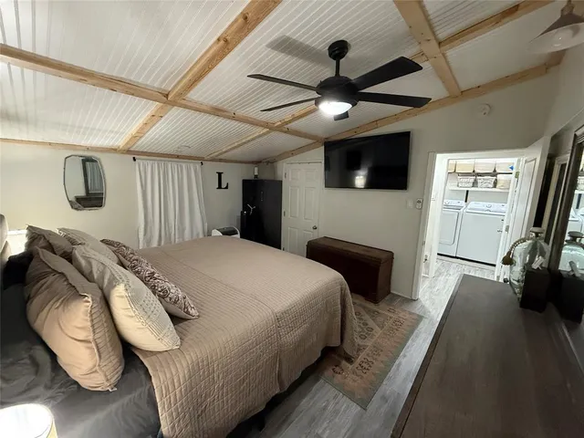 a bedroom with a bed a flat screen tv and a chandelier