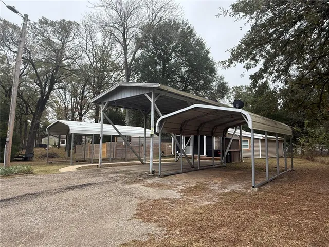 a view of a wooden house with large trees and wooden fence