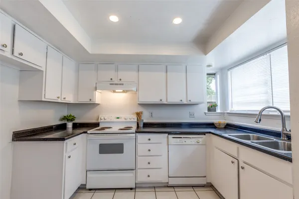 a kitchen with granite countertop white cabinets white appliances and sink