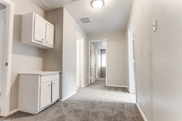 a view of a kitchen with white cabinets and window