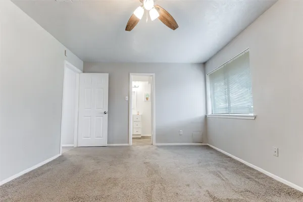 an empty room with chandelier fan and windows