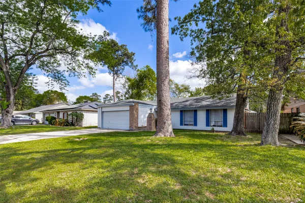 a view of a house with a big yard and large trees