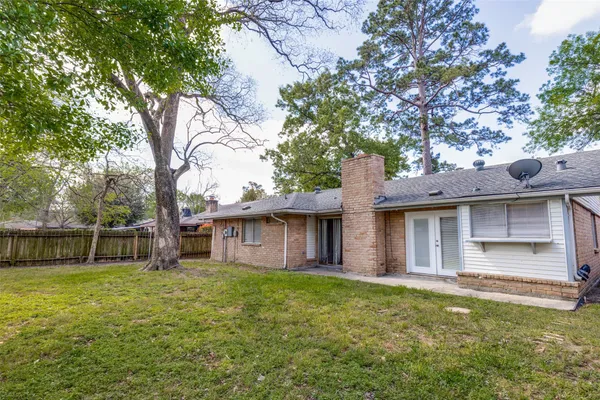 a view of a house with a yard plants and large tree