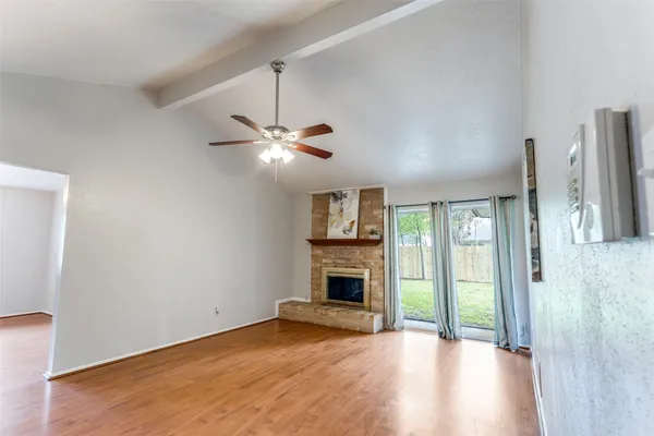 an empty room with fireplace wooden floor chandelier and windows