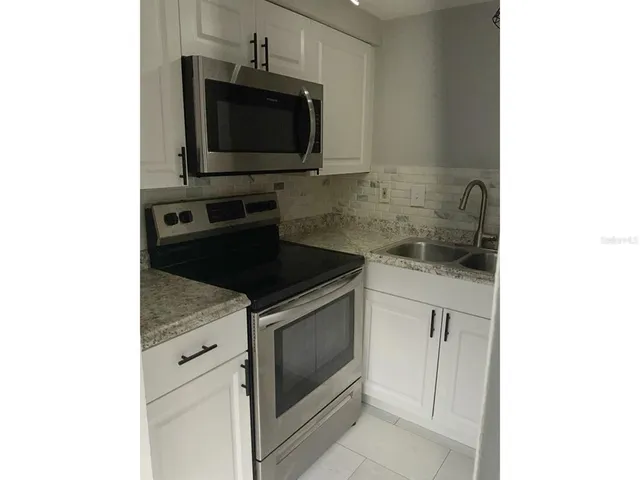 a kitchen with granite countertop white cabinets and stainless steel appliances