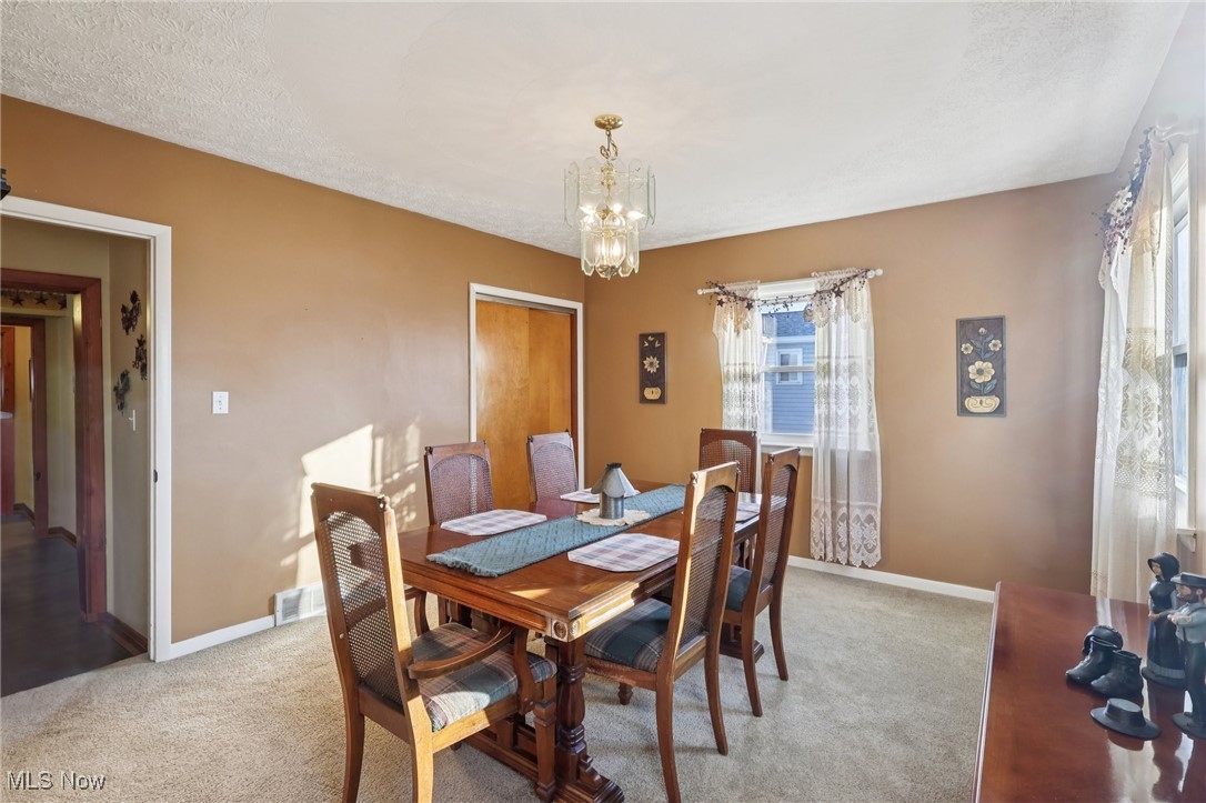 472 Stephens Road Akron, OH 44312 - Photo 14 of 46 4th bedroom currently used as a dining room with healthy amount of natural light, light colored carpet, a chandelier, and a textured ceiling