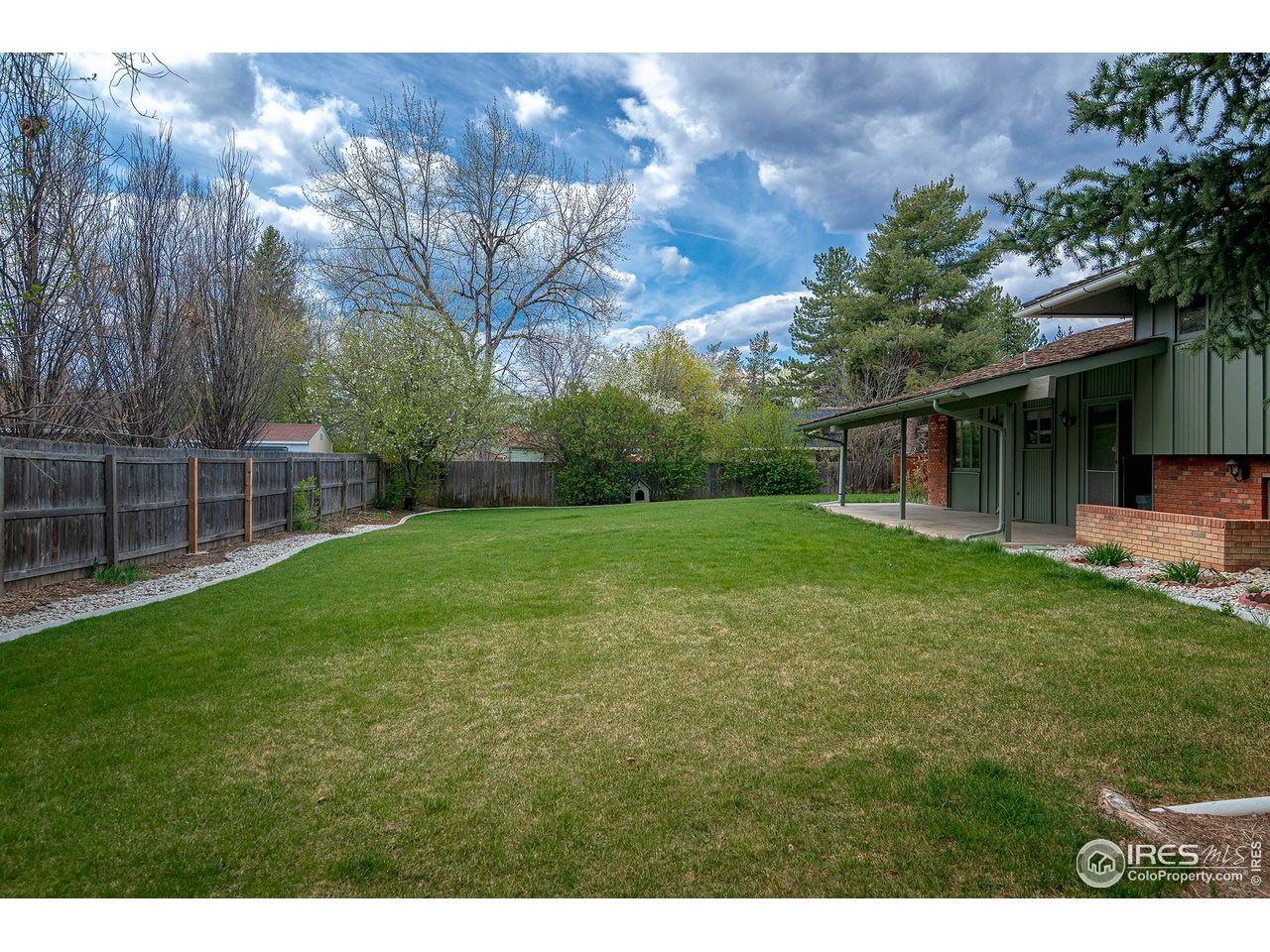6844 Roaring Fork Trail Boulder, CO 80301 - Photo 30 of 37 a backyard of a house with plants and large tree
