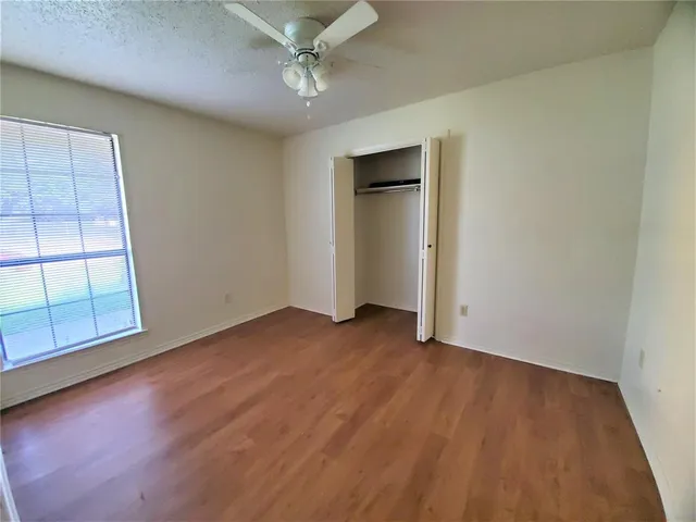 an empty room with wooden floor cabinet and windows