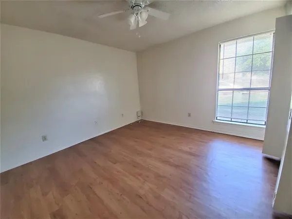 an empty room with wooden floor chandelier fan and windows